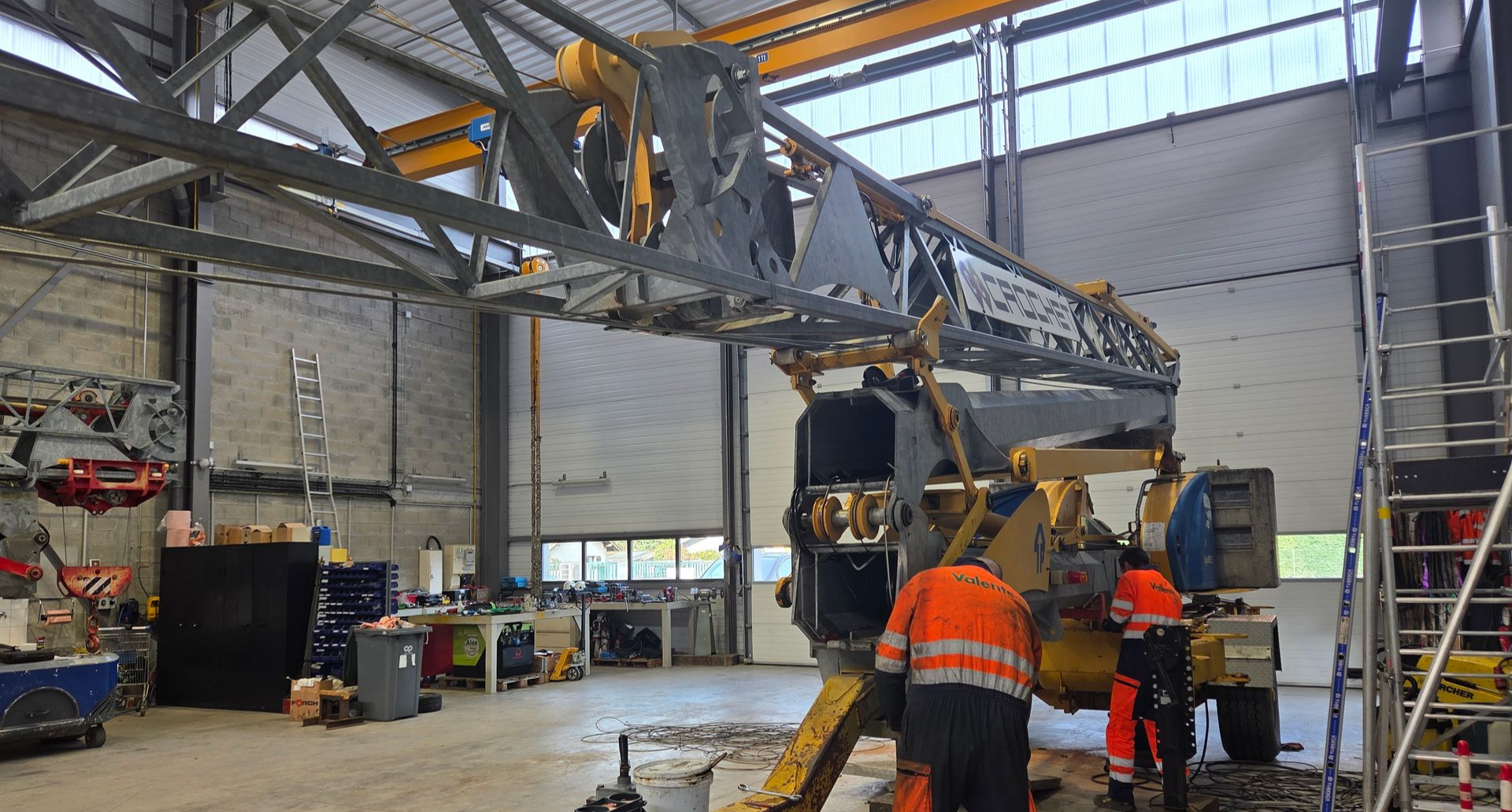 Réparation d'une grue de chantier dans un atelier professionnel.