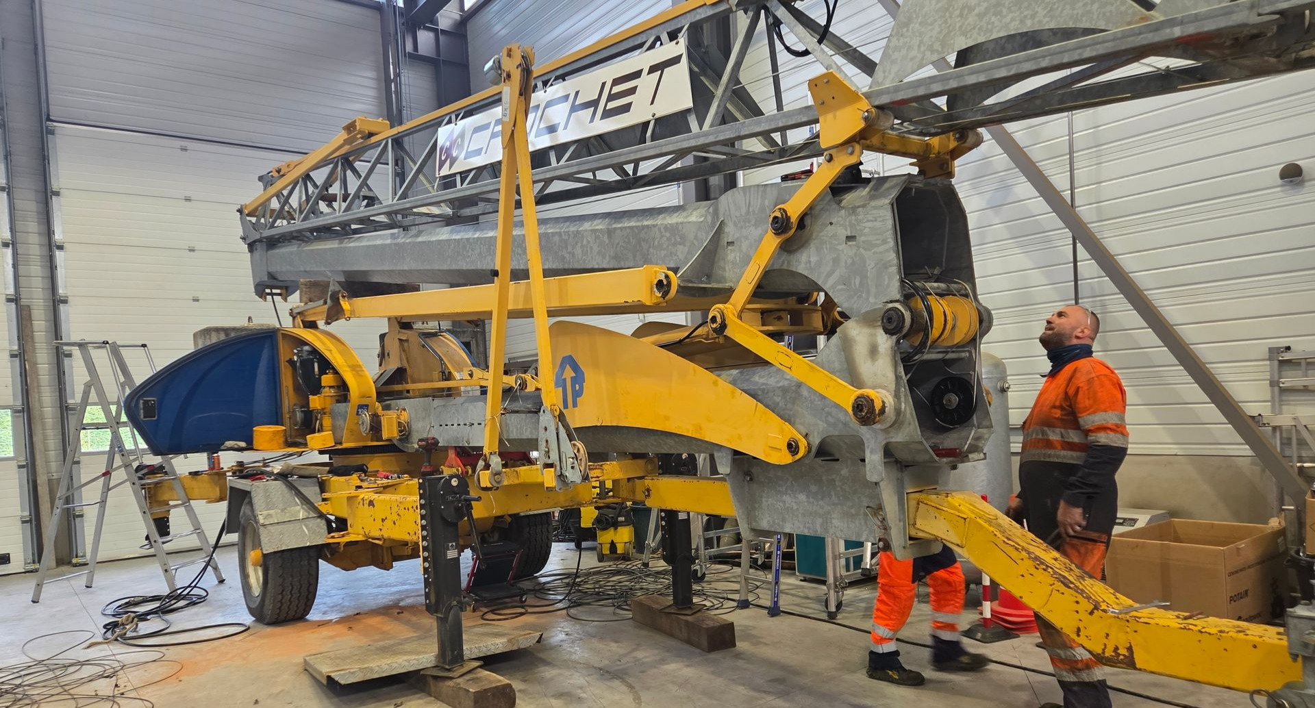 Une grue d'occasion dans un garage, prête à être reconditionnée.