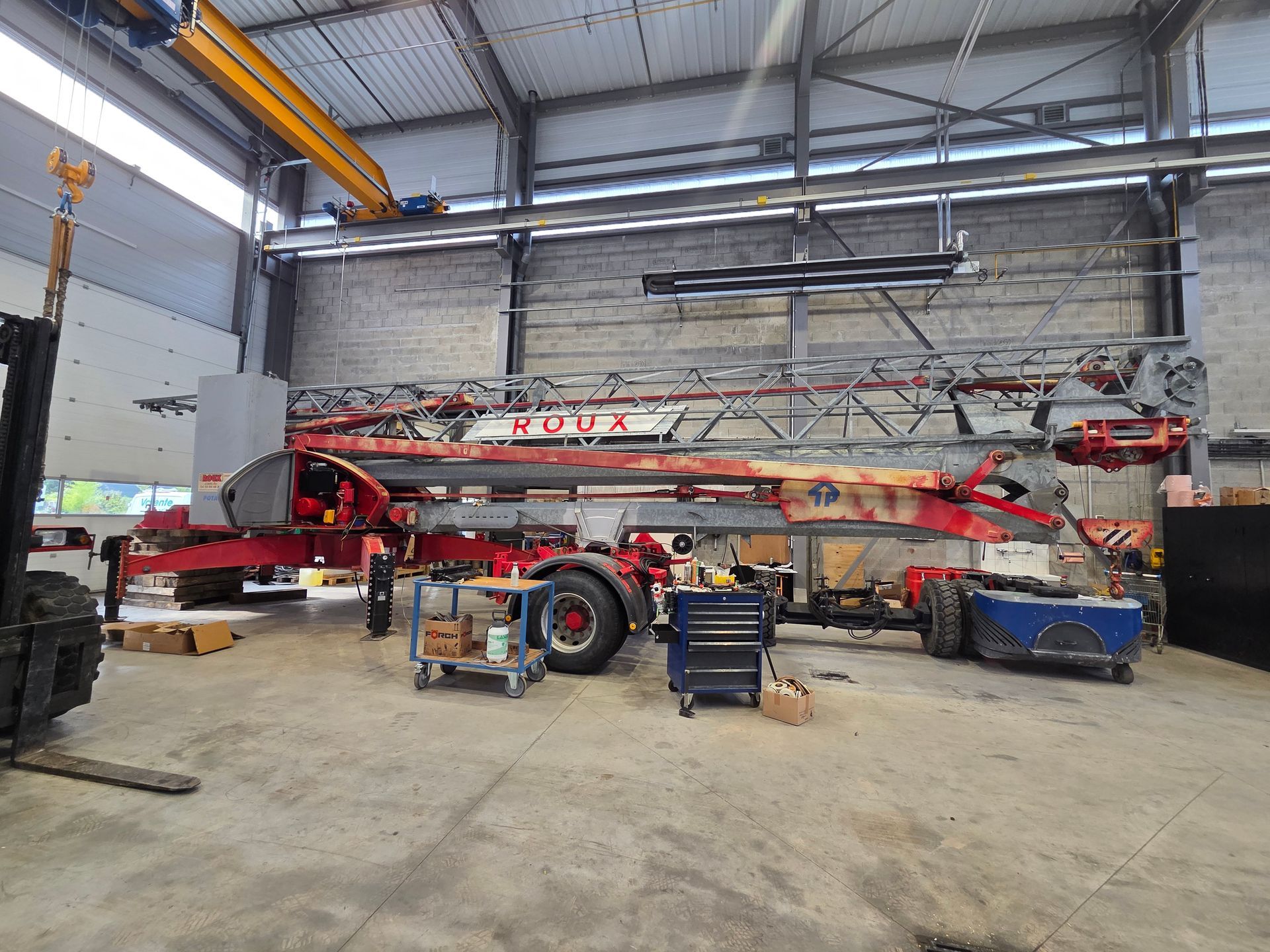 Une grande grue rouge et grise à l'intérieur d'un atelier.