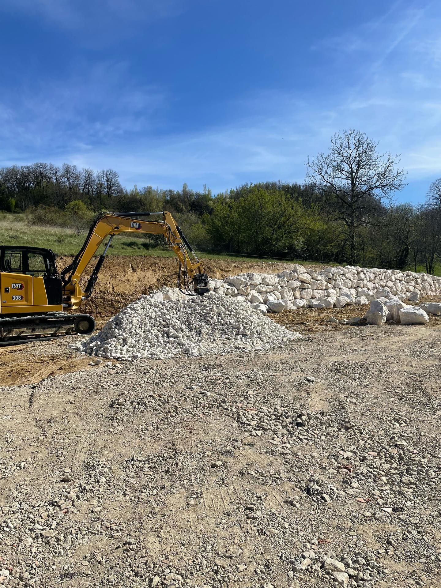 Une pelleteuse creuse une tranchée à côté d'une maison au toit de tuiles rouges.