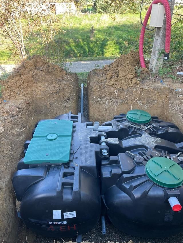 Des conduits colorés traversent une tranchée à côté d'un bâtiment.
