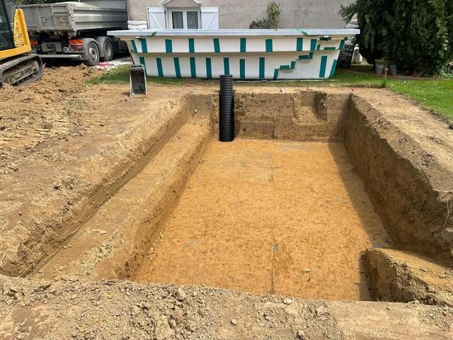 Une piscine rectangulaire entourée de gravier dans un jardin, à côté d'une maison moderne.