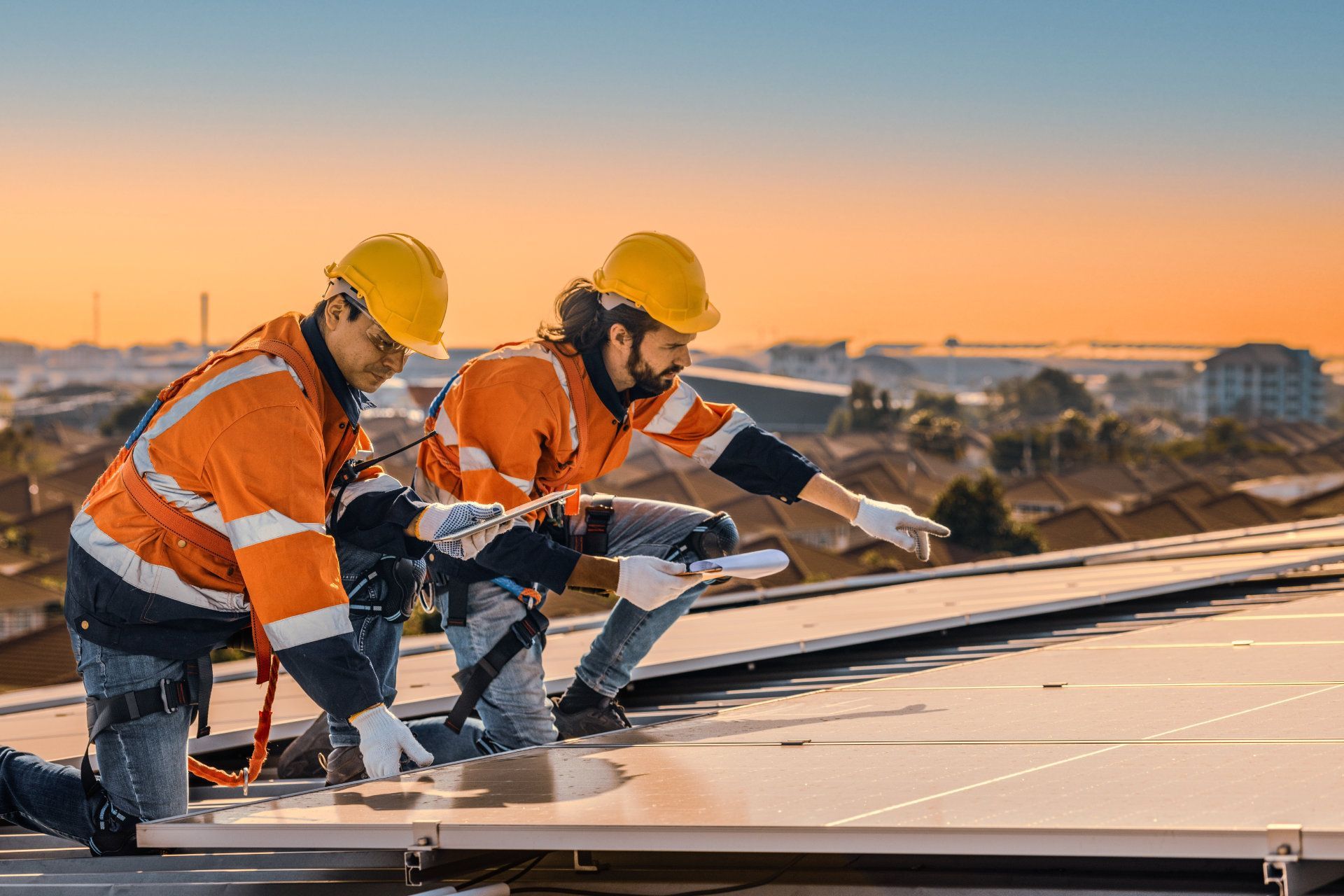 Zwei Bauarbeiter installieren Solarmodule auf dem Dach eines Gebäudes