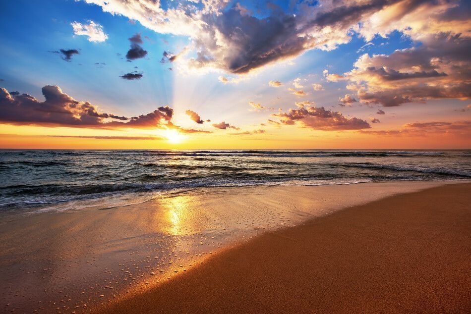 Una playa con una puesta de sol al fondo
