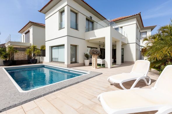 Una gran casa blanca con una piscina delante de ella.