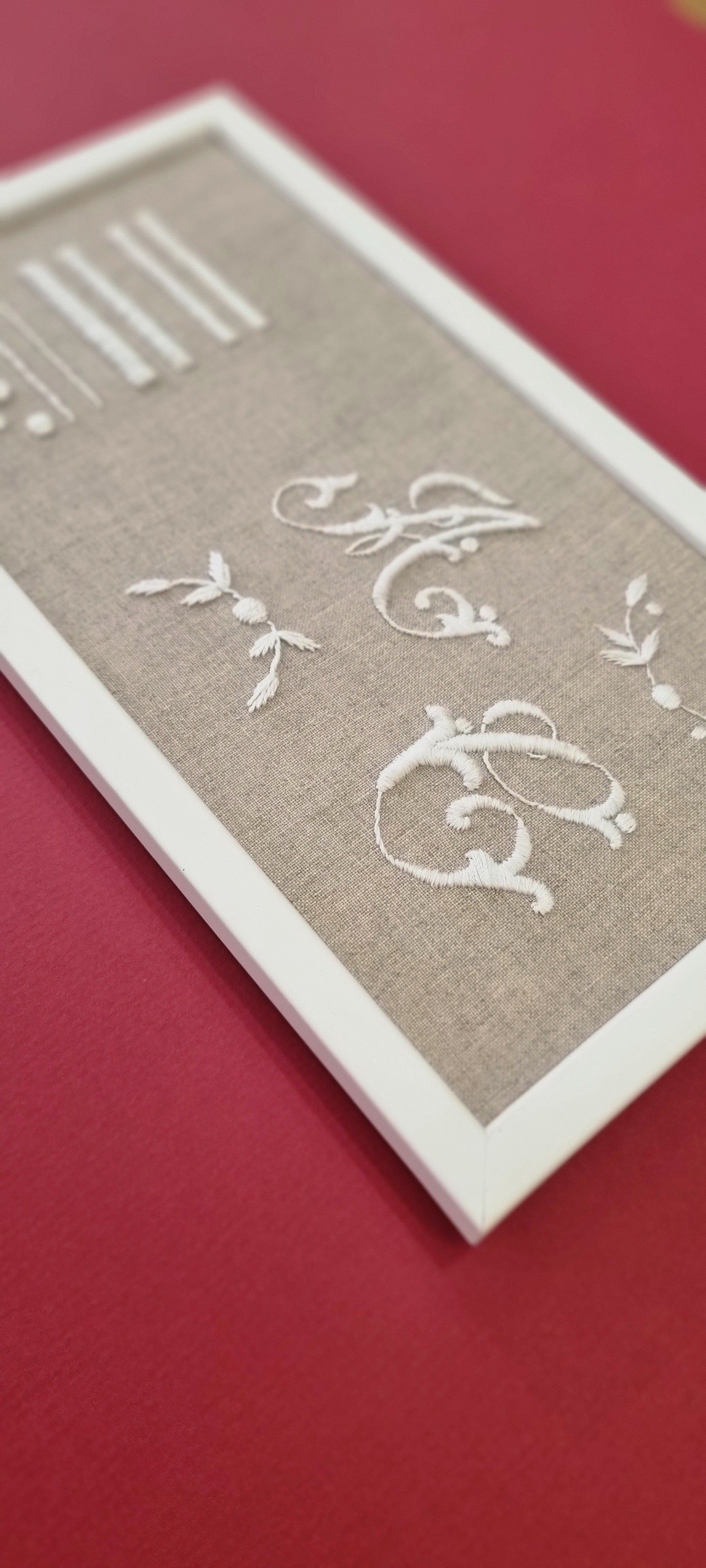 Lettres blanches brodées sur un fond beige