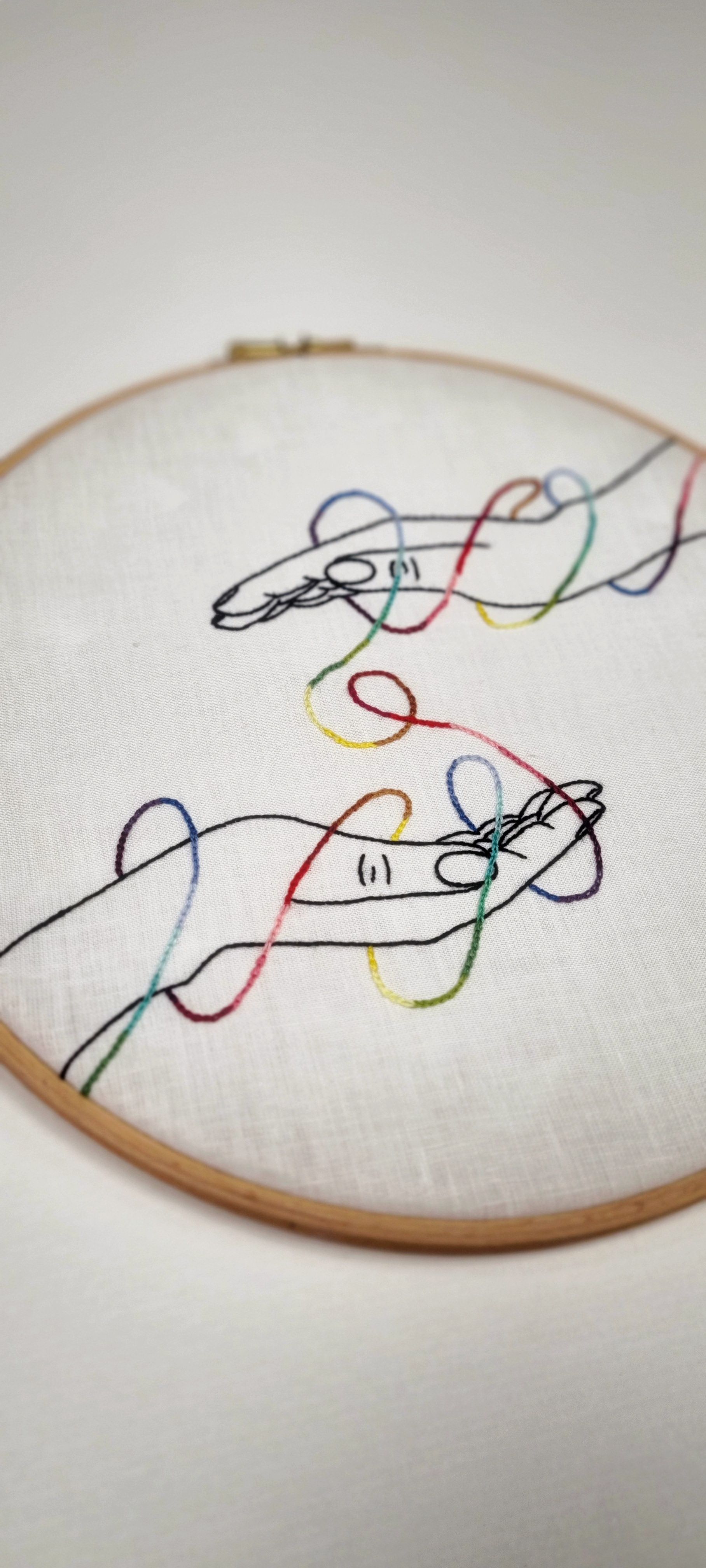 Mains entourées d'un fil de couleurs en broderie
