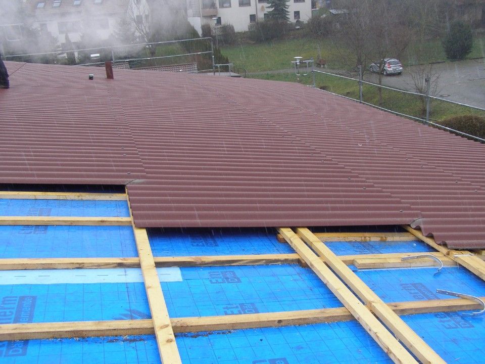 Verlegen von roten Dachziegeln auf blauem Untergrund