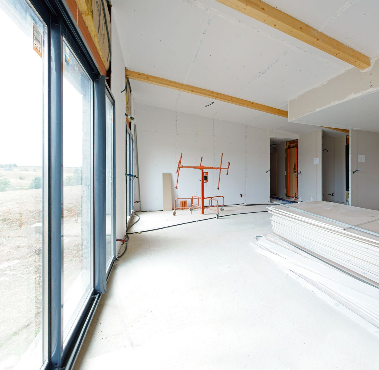 Pièce avec mur bicolore, fournitures de peinture, échelle et suspensions. Un mur blanc est peint en bleu.