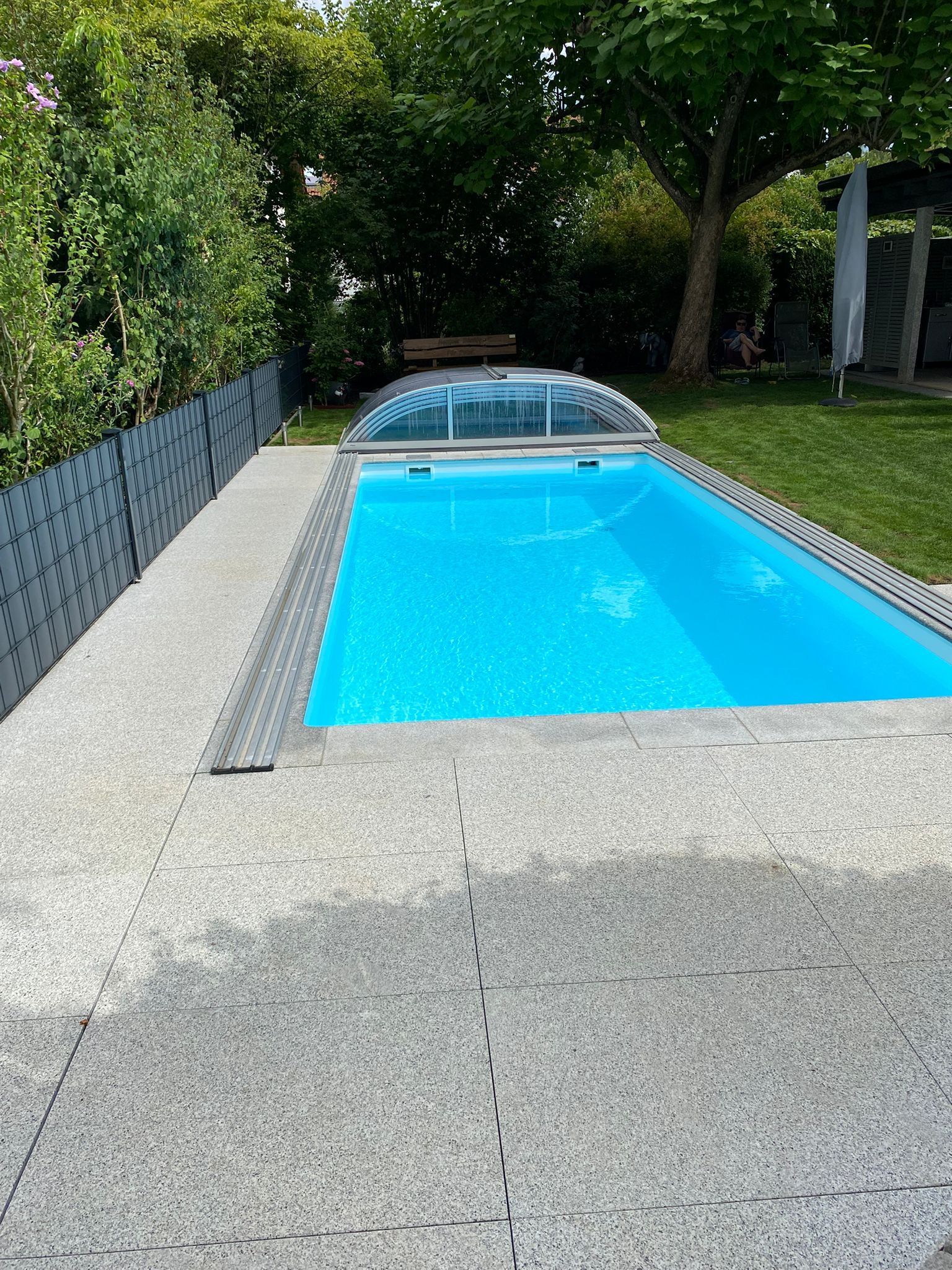Gartenpool mit leuchtend blauem Wasser, umgeben von Kies und Grün