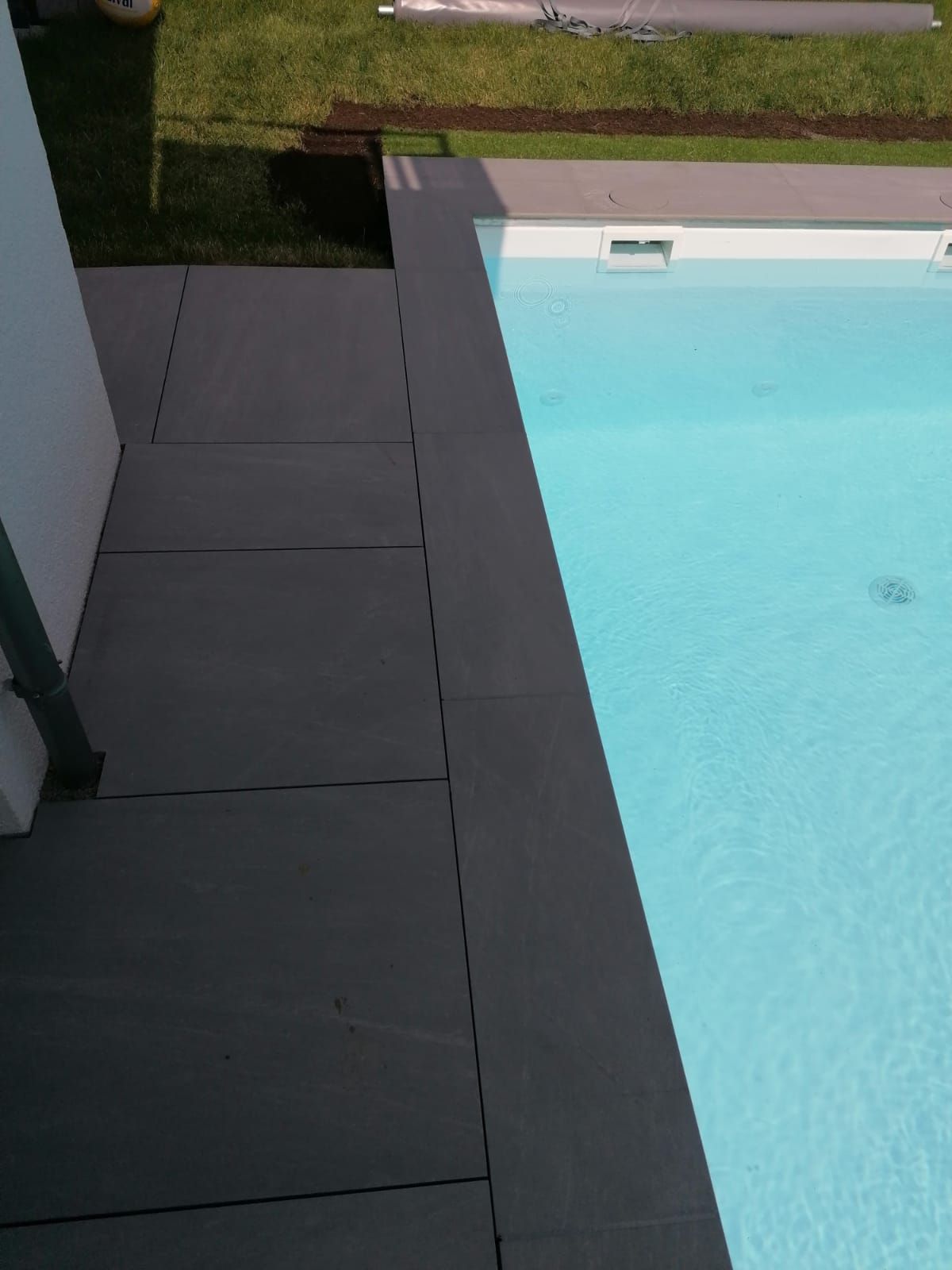 Pool mit dunkelgrauer Terrasse und klarem, blauem Wasser