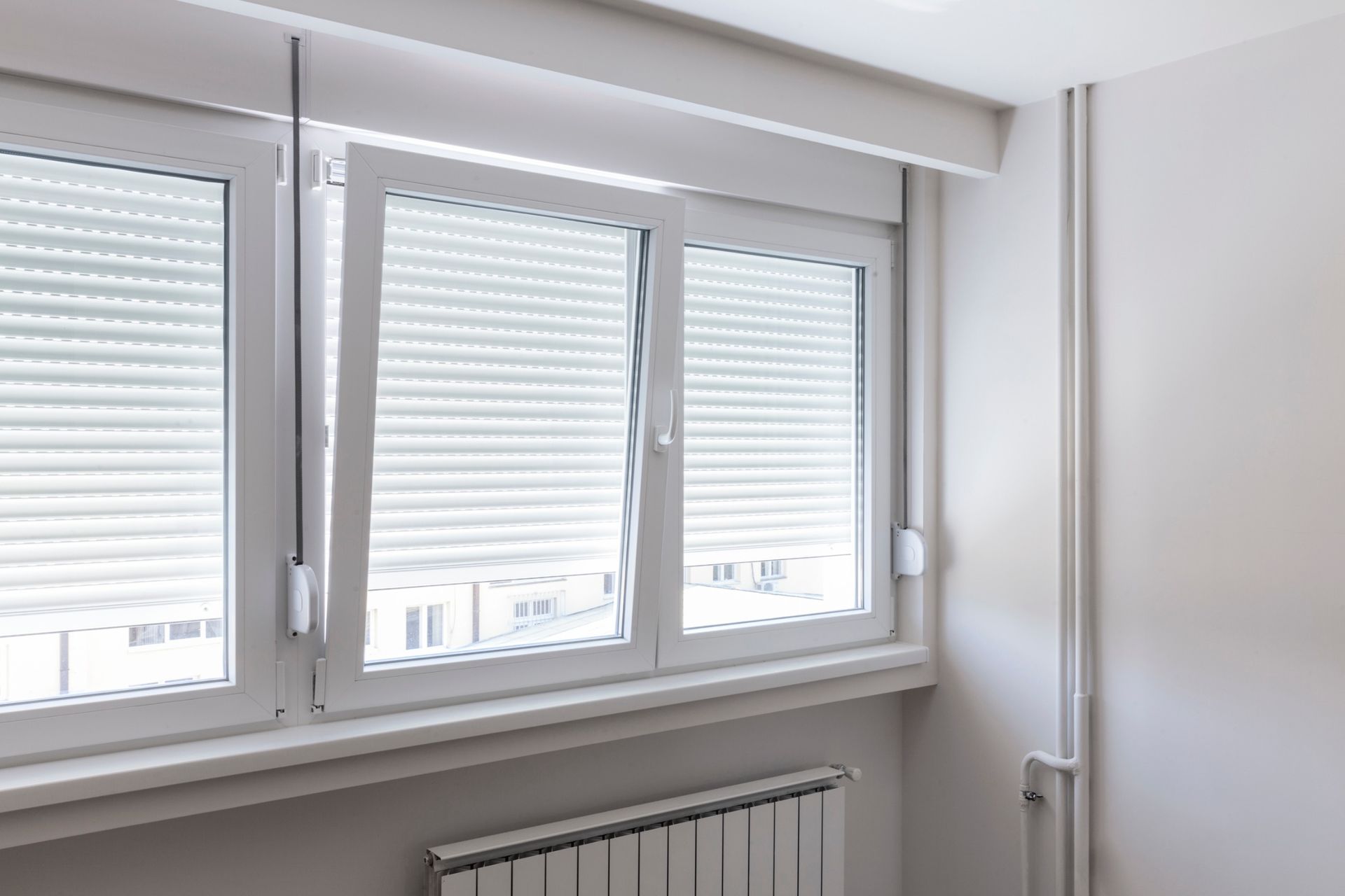Una habitación con dos ventanas y un radiador.