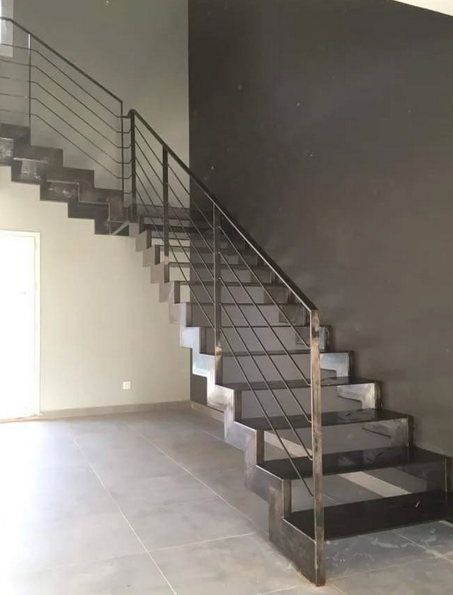 Una escalera con barandilla de metal en una habitación vacía.