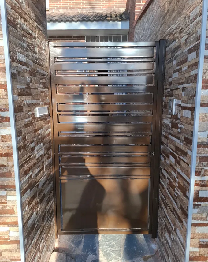 Una puerta de acero inoxidable está entre dos paredes de ladrillo.