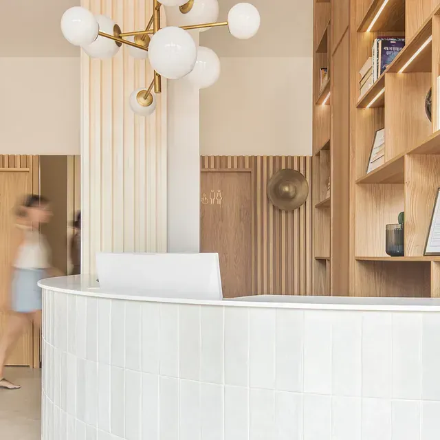 Una mujer pasa junto a un mostrador de recepción blanco en una habitación.