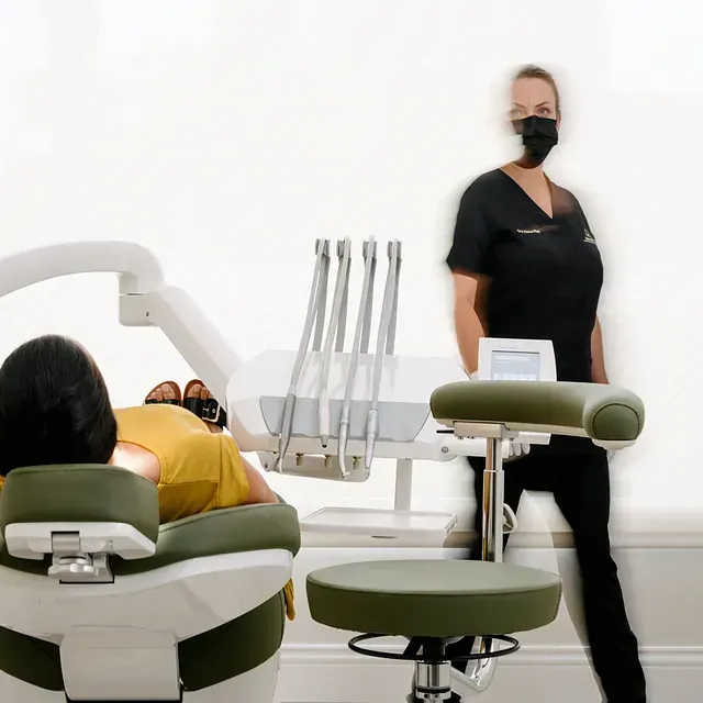 Una mujer con una máscara está junto a un hombre en una silla dental.