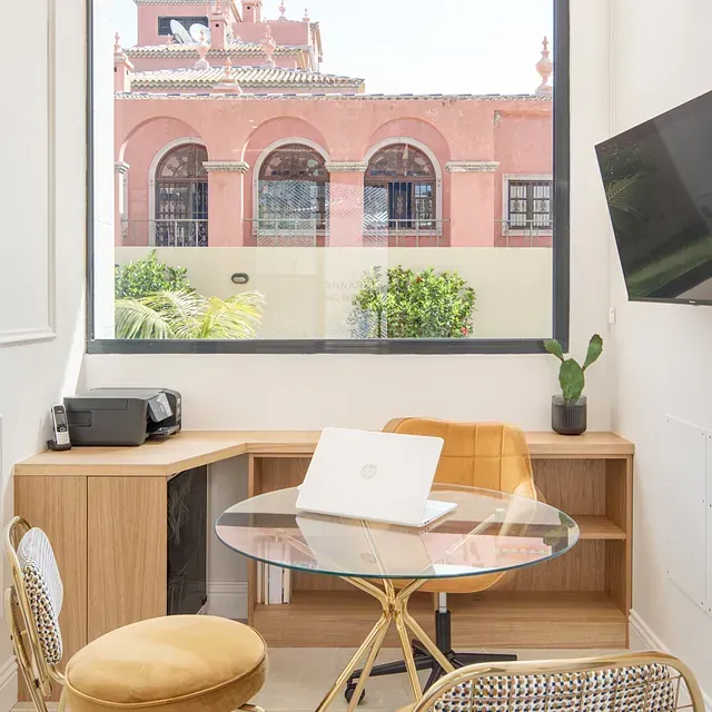Una habitación con una mesa y sillas y una computadora portátil encima.