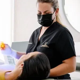 Una mujer que lleva una mascarilla y guantes le está dando un masaje a una mujer.