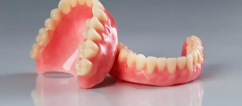 Un par de dentaduras postizas colocadas una encima de otra sobre una mesa.