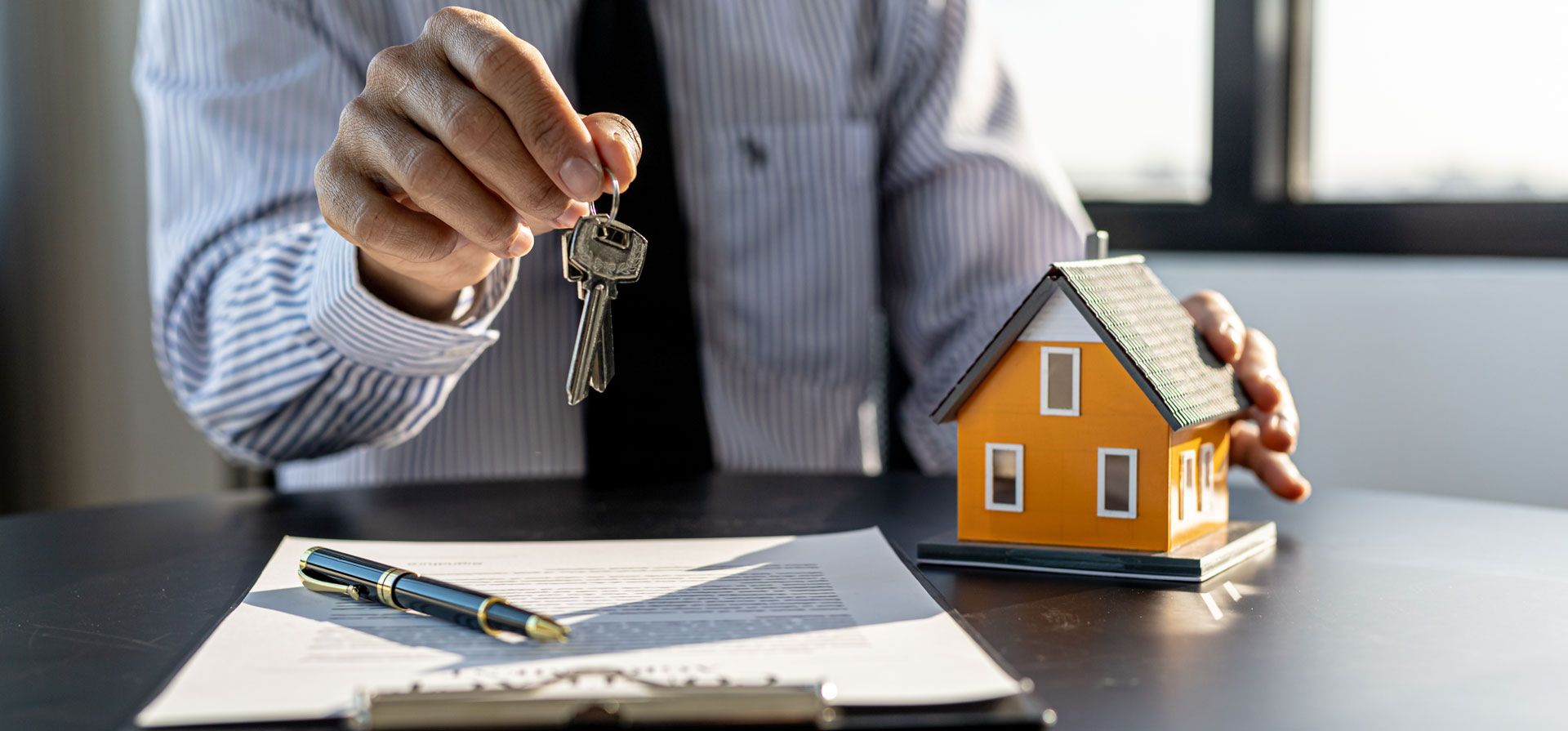 Un professionnel de l'immobilier tend les clés d'une maison à louer