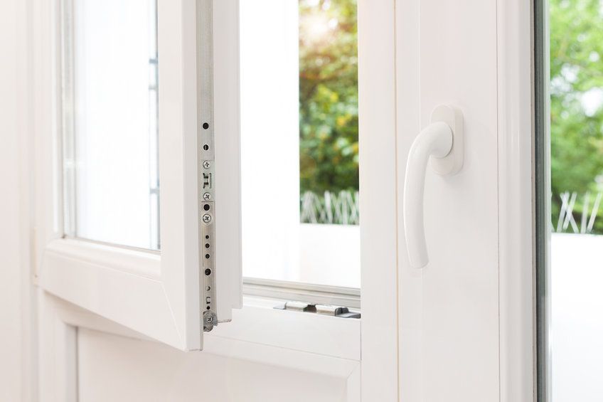 Un primer plano de una ventana abierta con una manija blanca.