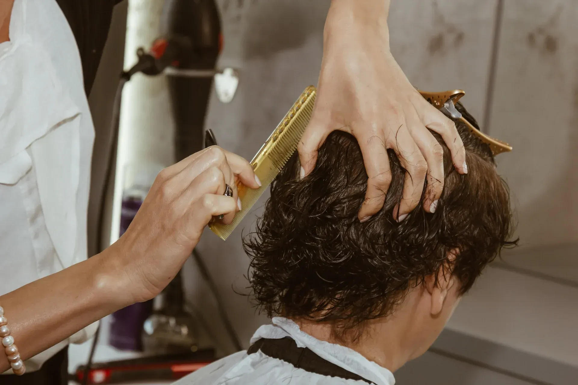 Peluquero cortando el pelo con peine y tijeras en un salón.
