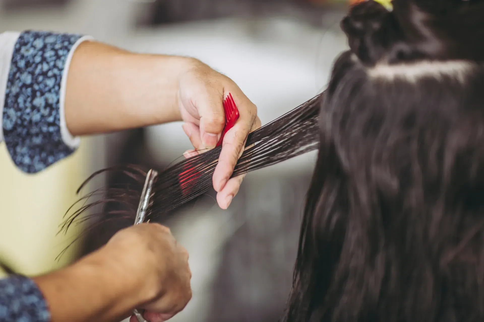 Peluquero cortando cabello largo y oscuro con tijeras.
