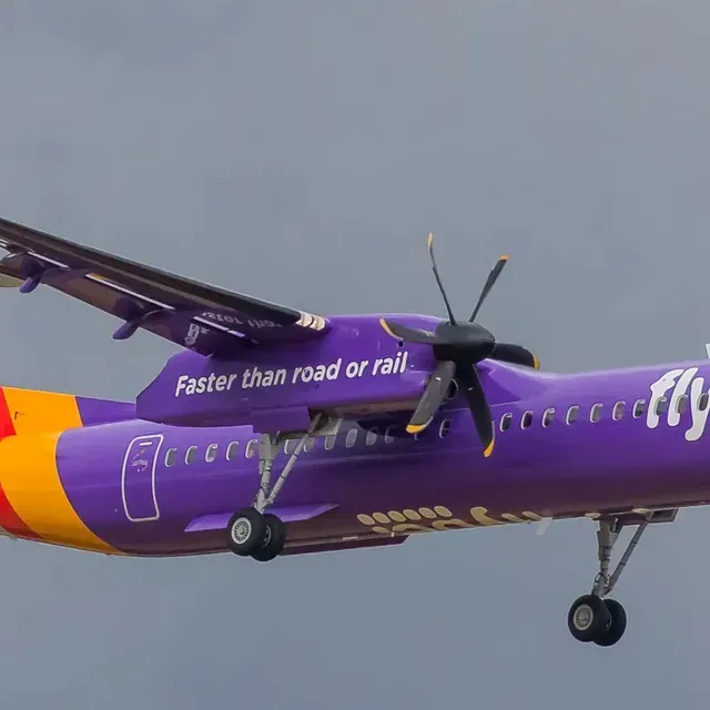 Un avión de color morado y amarillo está volando en el cielo.