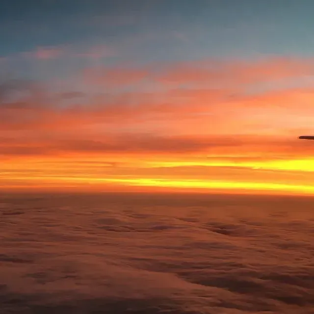 Un avión está volando sobre las nubes al atardecer.