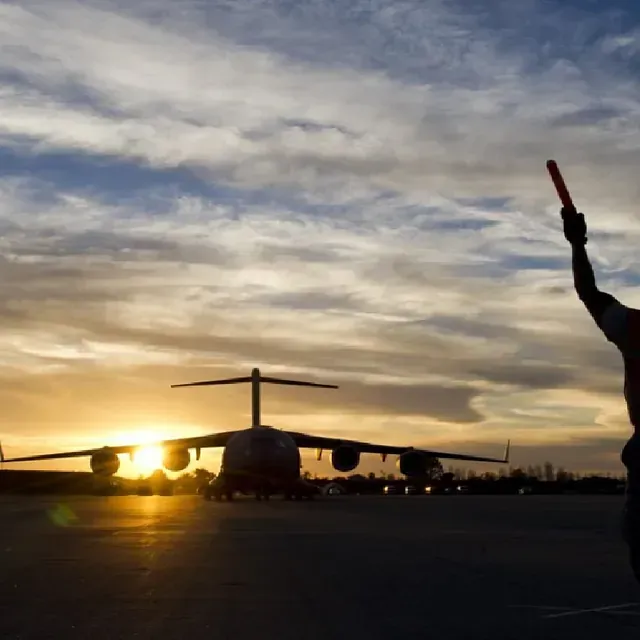 Un hombre sostiene una luz roja delante de un avión.