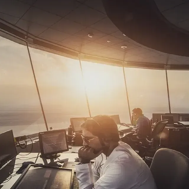 Un hombre con auriculares está sentado en un escritorio frente a un monitor de computadora.