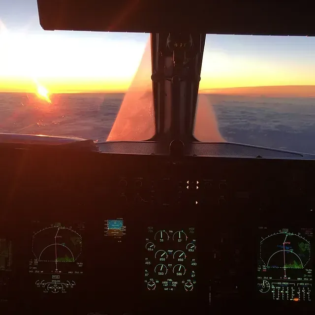 Una cabina de un avión con la puesta de sol al fondo.