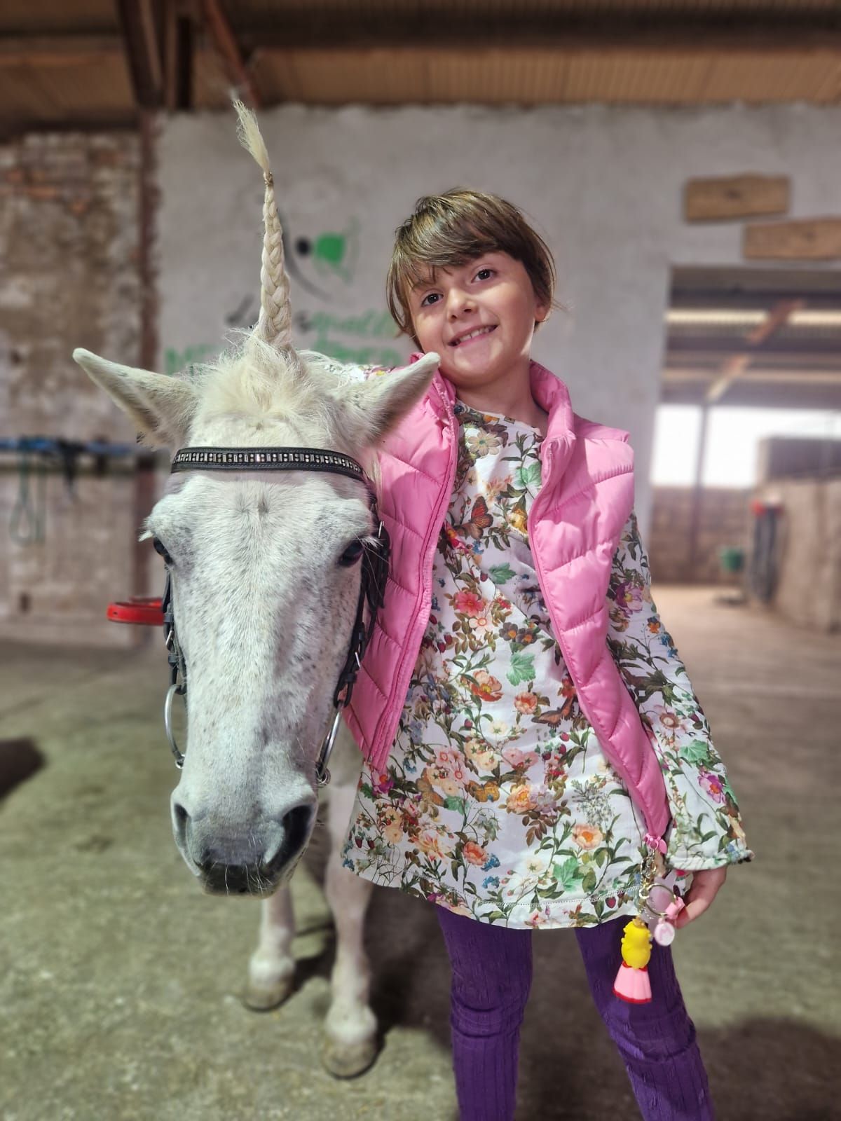Ein kleines Mädchen steht neben einem weißen Pferd mit einem Einhornhorn.