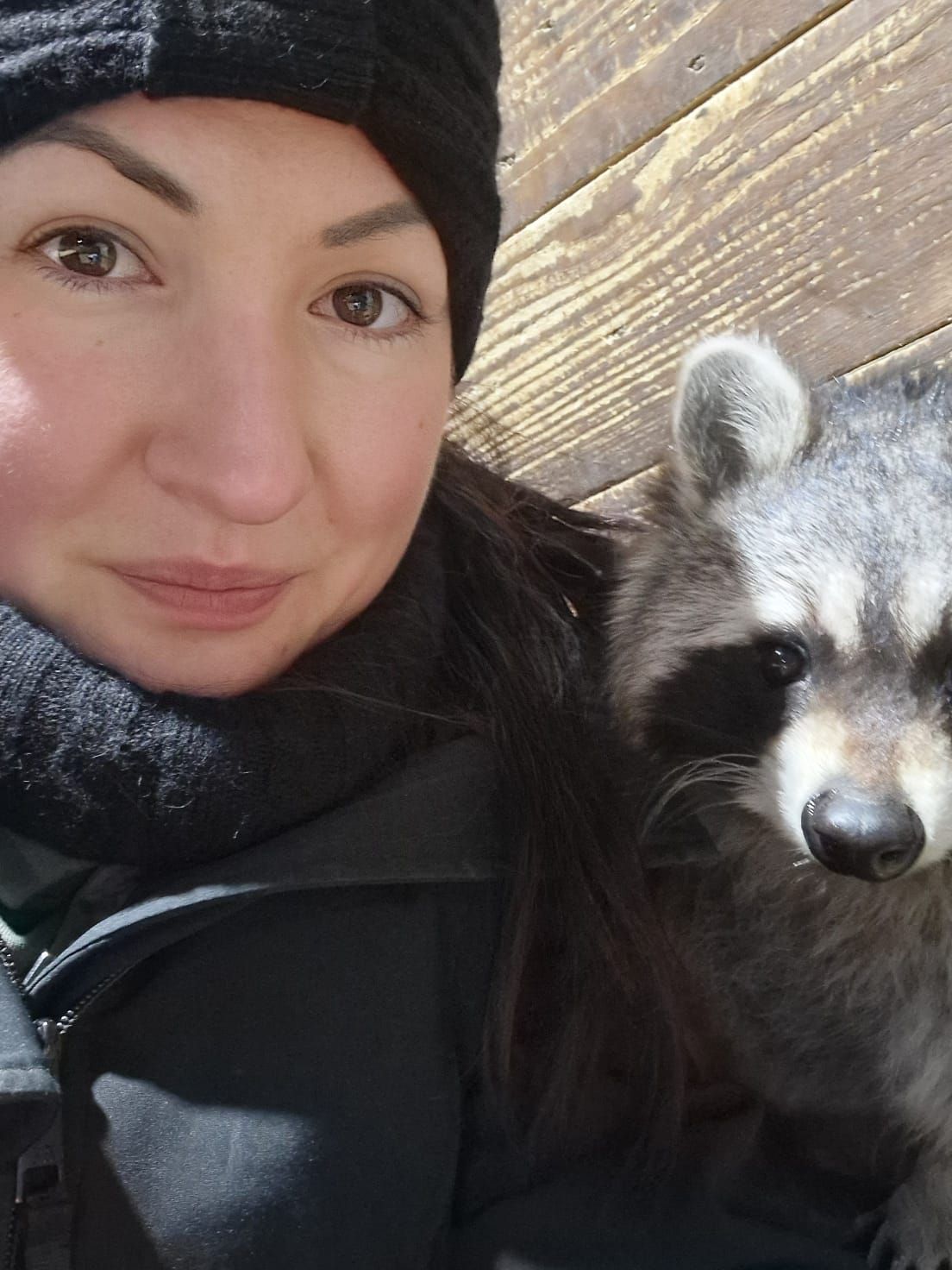Eine Frau posiert für ein Foto mit einem Waschbären