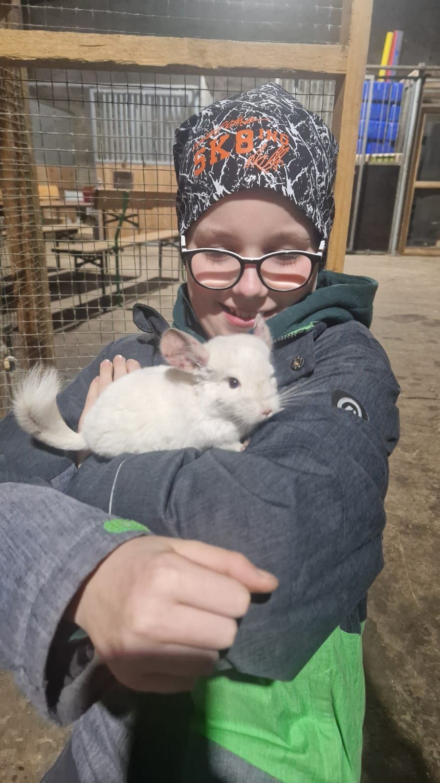 Ein kleiner Junge hält ein kleines weißes Kaninchen in seinen Armen.