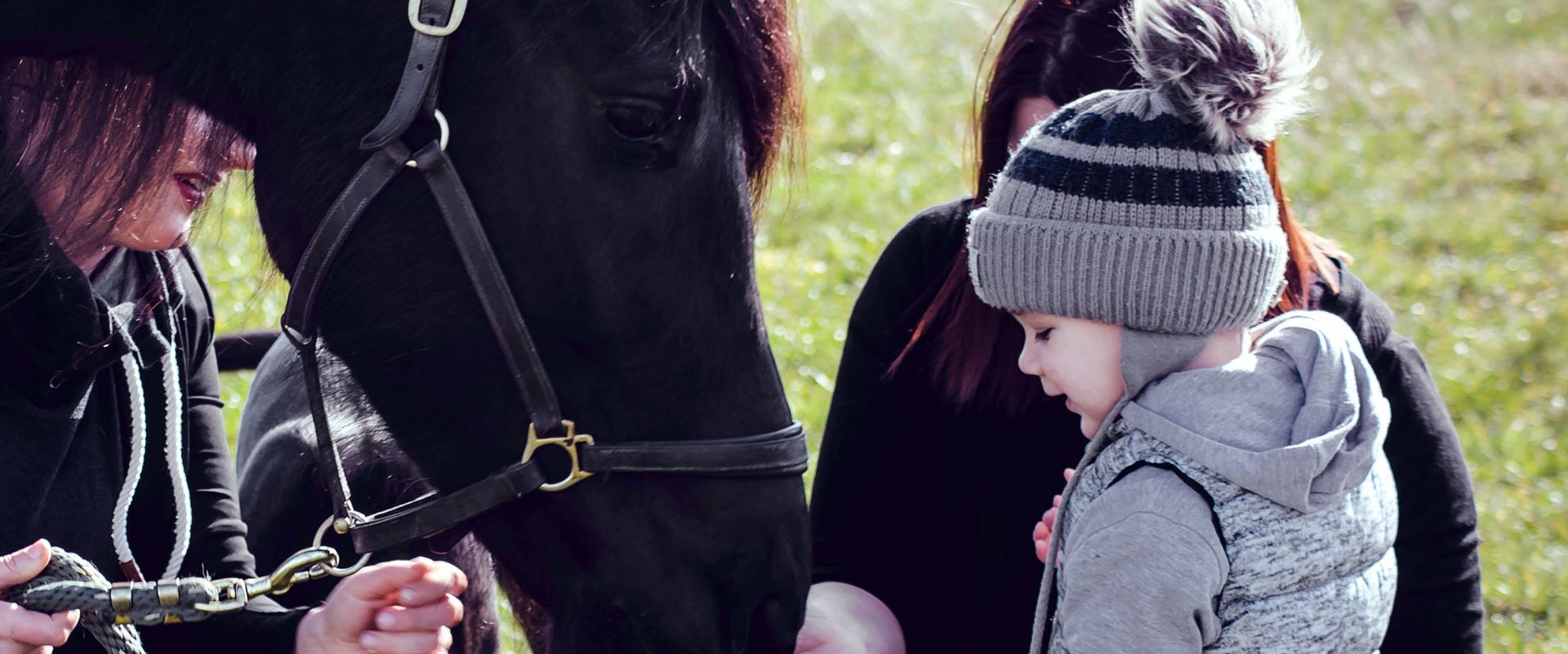 Eine Frau und ein Kind stehen neben einem schwarzen Pferd.