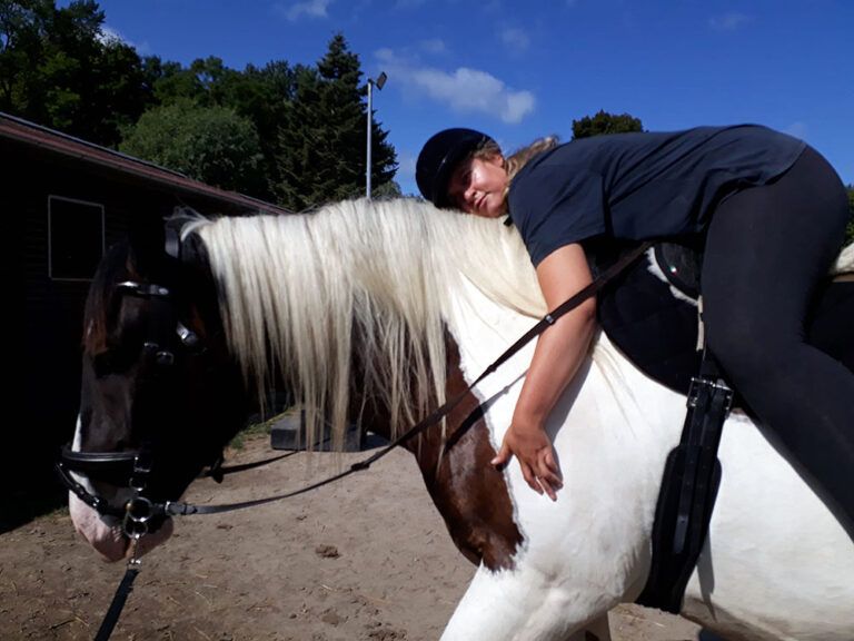 Eine Person, die auf einem braun-weißen Pferd liegt