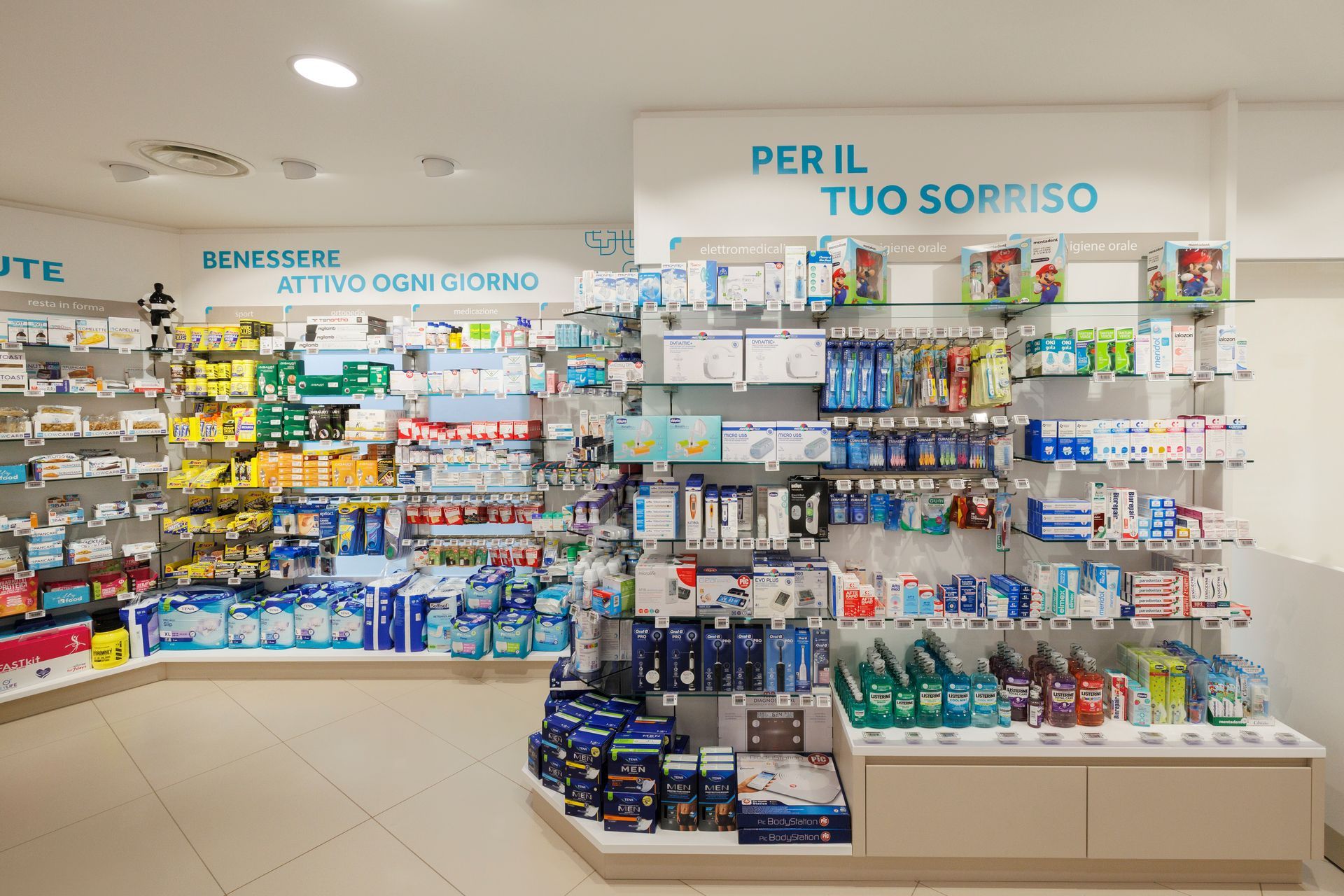 Un corridoio luminoso di una farmacia con scaffali pieni di medicinali, articoli da toeletta e prodotti per l'igiene dentale sotto l'insegna 