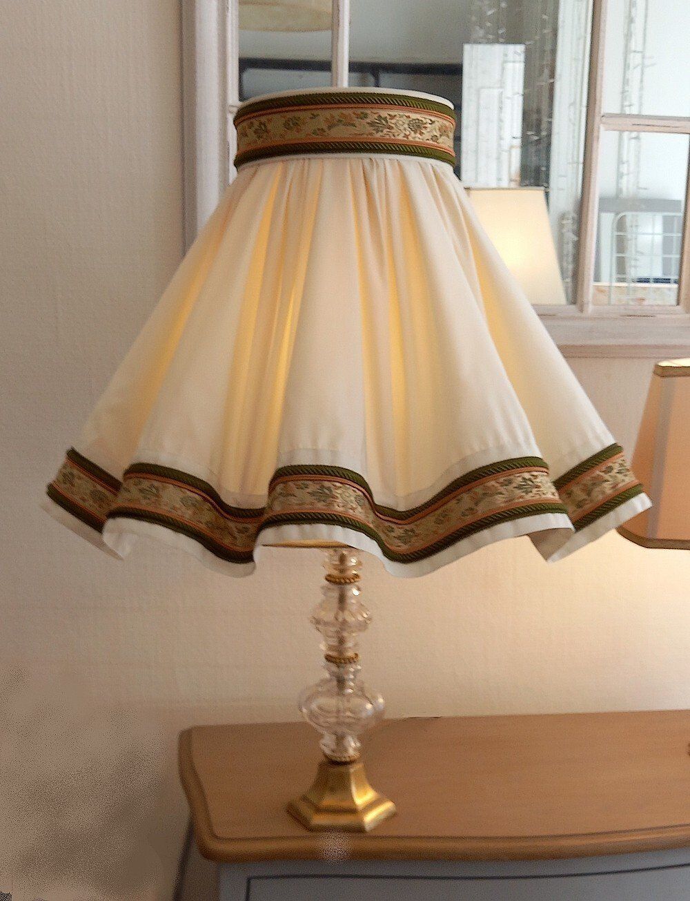 Abat-jour ondulé parisien détails rouge et vert posé sur un meuble