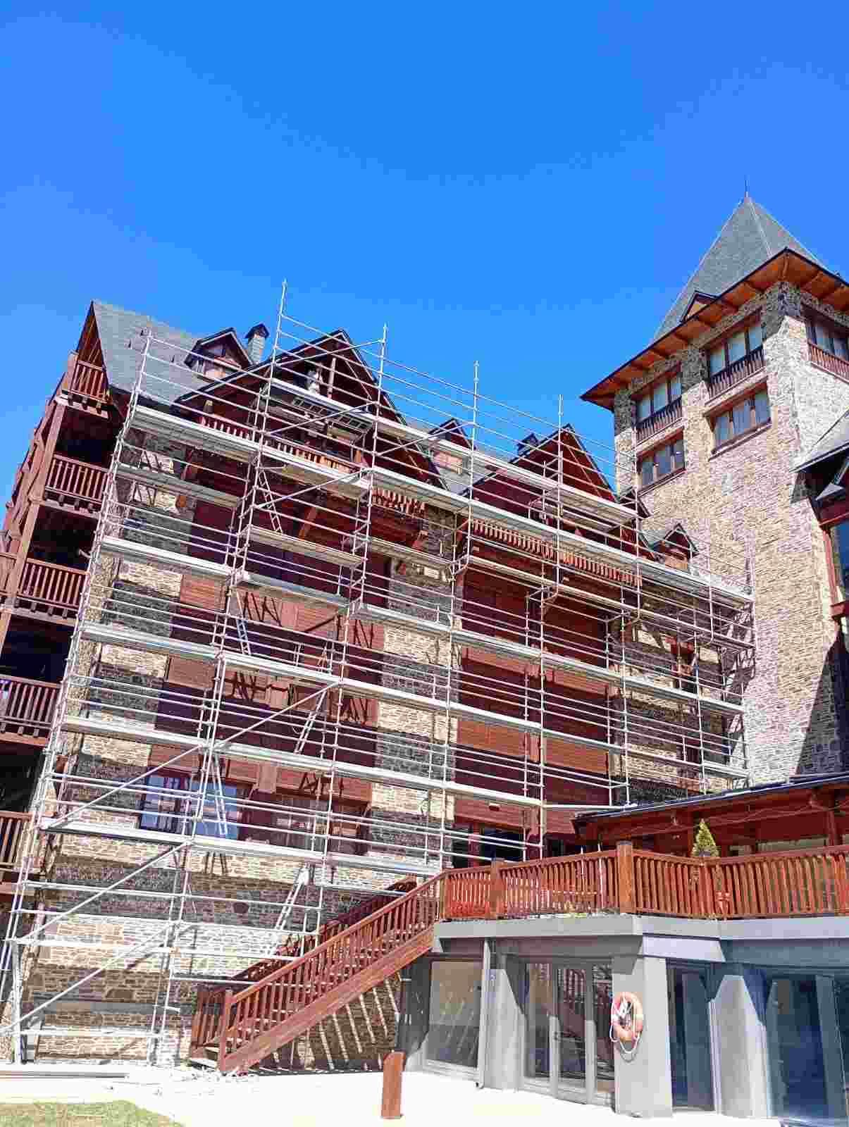 Edificio de estilo chalet cubierto de nieve, con balcones rojos bajo un cielo azul despejado