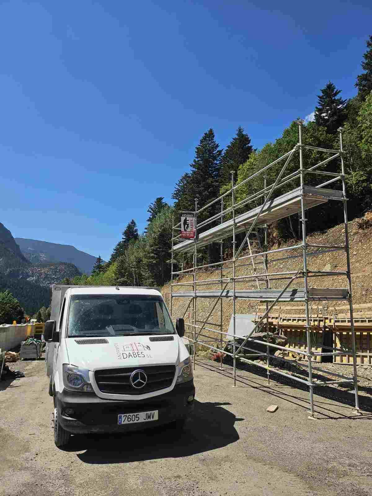 Edificio de ladrillo en construcción, con andamios y un terreno de tierra en primer plano bajo un cielo nublado