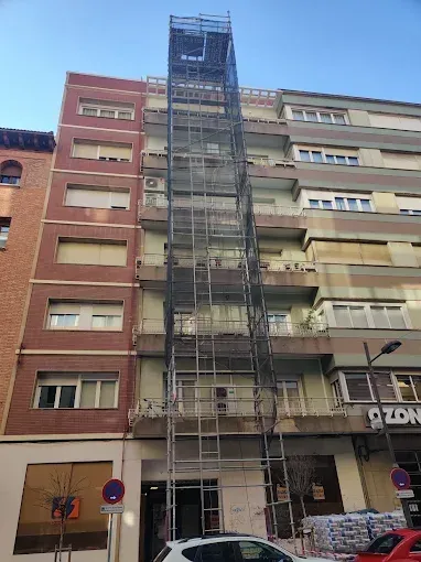 Edificio de apartamentos con un alto montacargas central de andamios en una calle de la ciudad