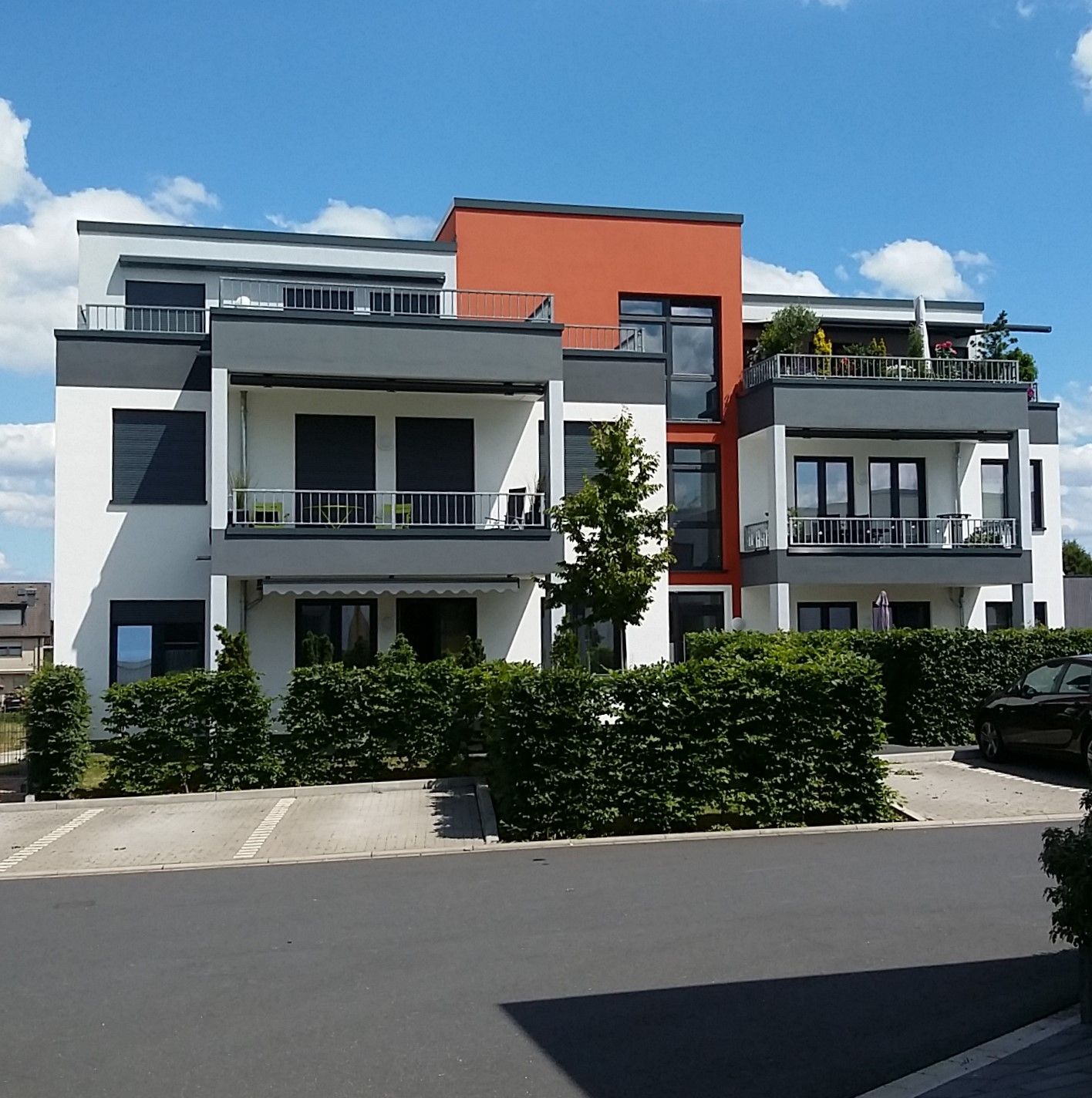 Eine Frau gibt einem Mann vor einem Musterhaus einen Schlüsselbund.