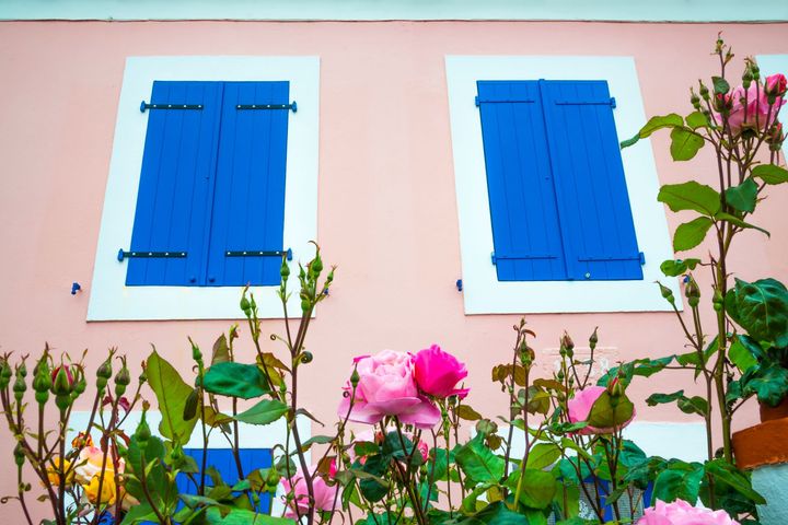 Une façade avec des volets battants bleus fermés