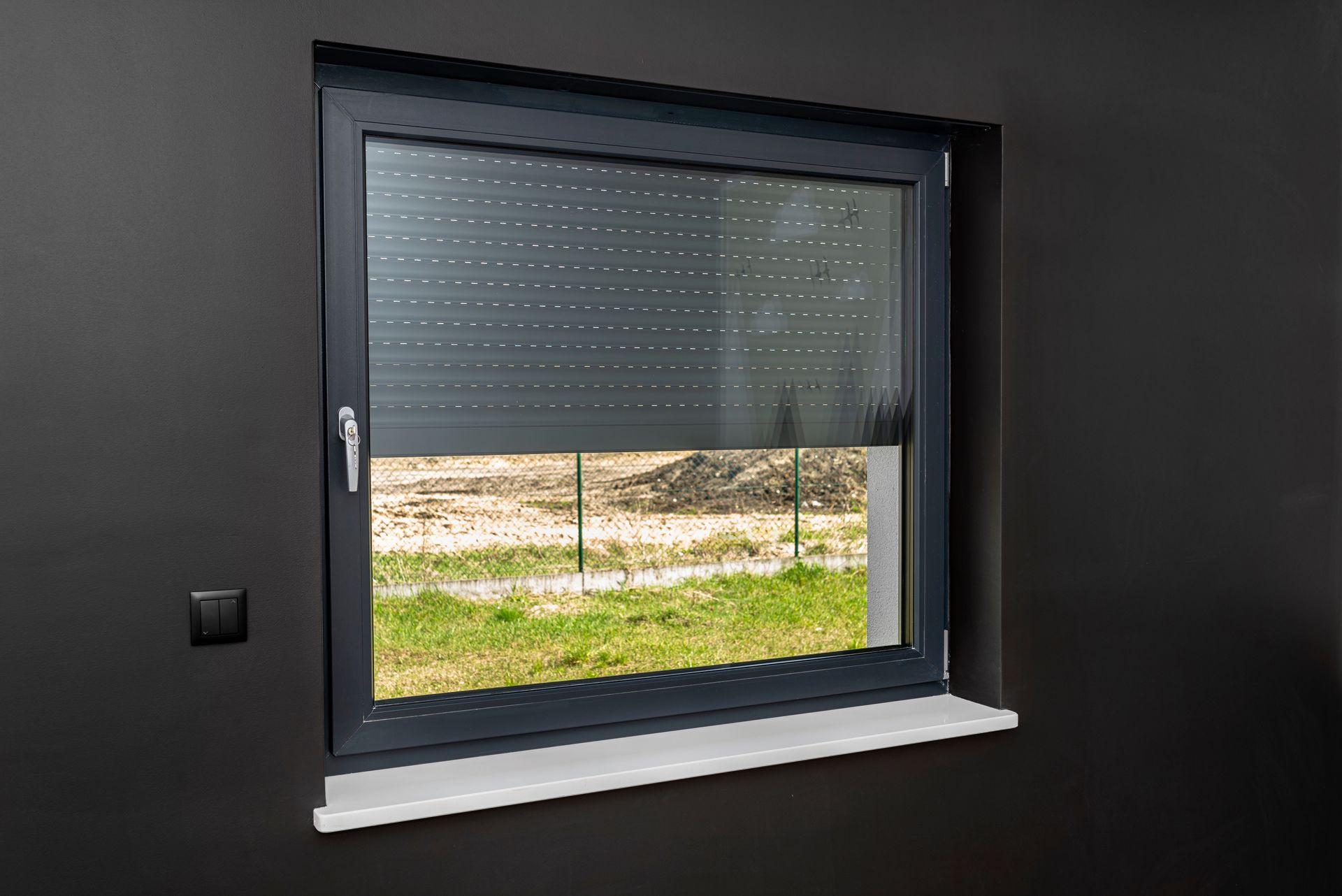 Un volet roulant gris anthracite à moitié ouvert vu de l'intérieur d'une pièce
