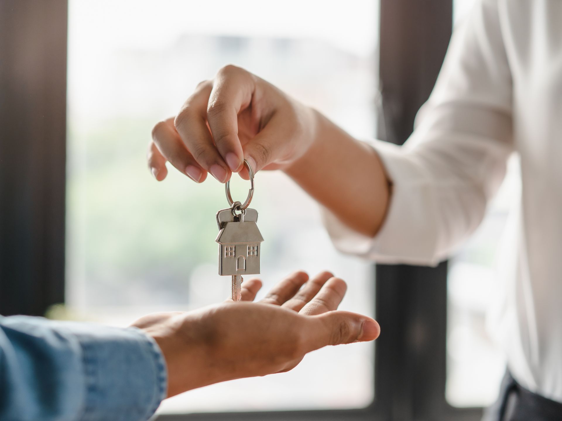 Une femme donne une clé avec un porte-clé maison à un homme