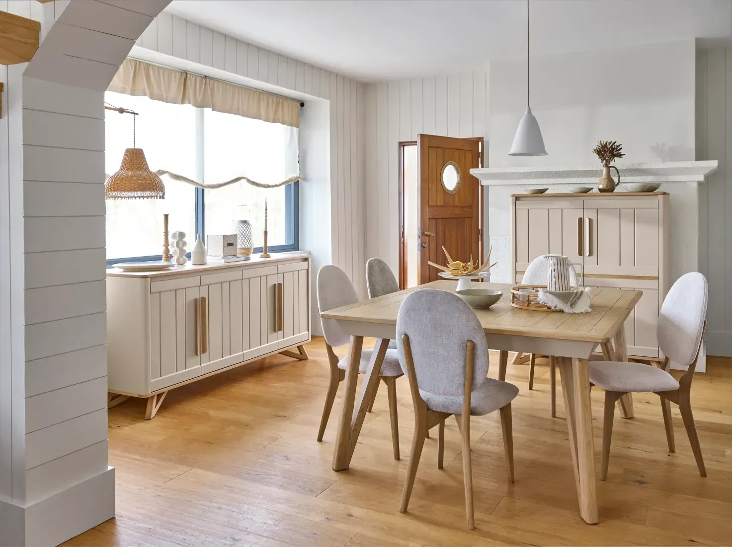 Salle à manger avec meubles en bois clair, comprenant une table et des chaises et un buffet.