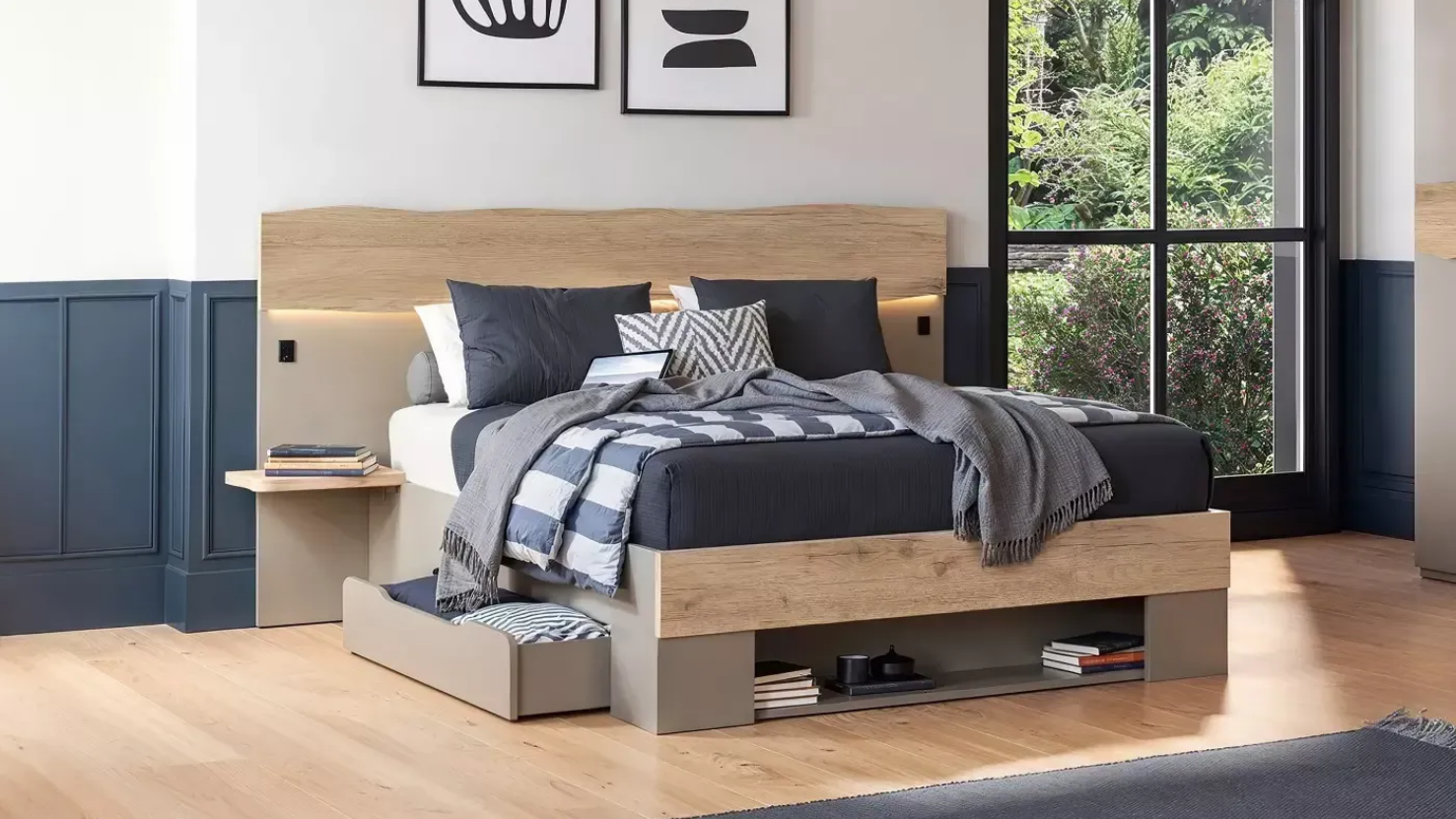 Chambre moderne avec un cadre de lit en bois, une tête de lit, des rangements et des coussins et couvertures décoratifs.