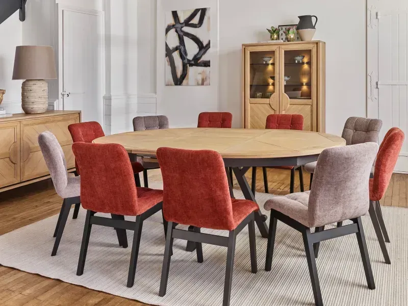 Salle à manger avec table ovale en bois, dix chaises rembourrées et un buffet.