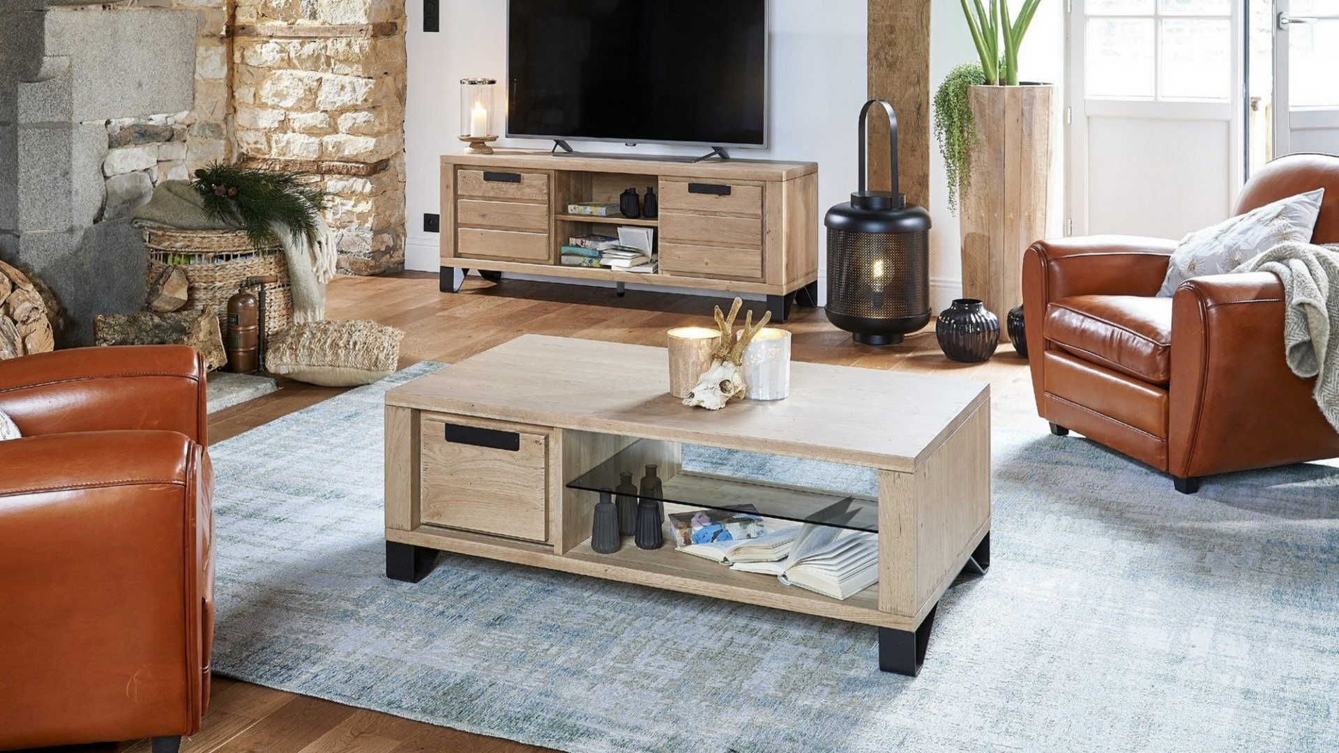 Salon avec meubles en bois clair, fauteuils en cuir, télévision et tapis.